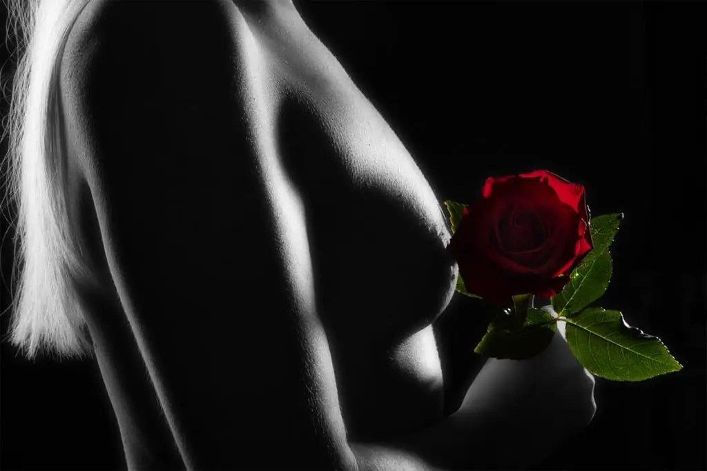 nackte Frau sw mit roter Rose vor der Brust